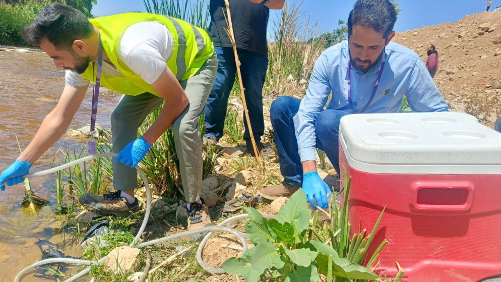 مختصون يأخذون عينات من مياه سيل الزرقاء. (وزارة البيئة)
