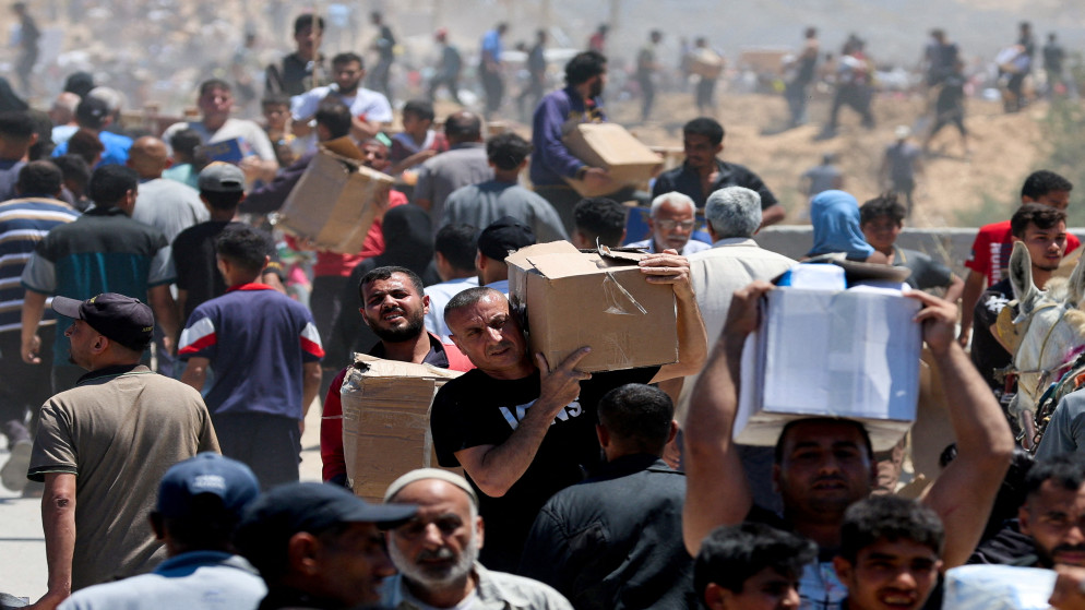فلسطينيون يحملون إمدادات المساعدة التي تلقوها من مؤسسة غزة الإنسانية، 29 أيار 2025. (رويترز)