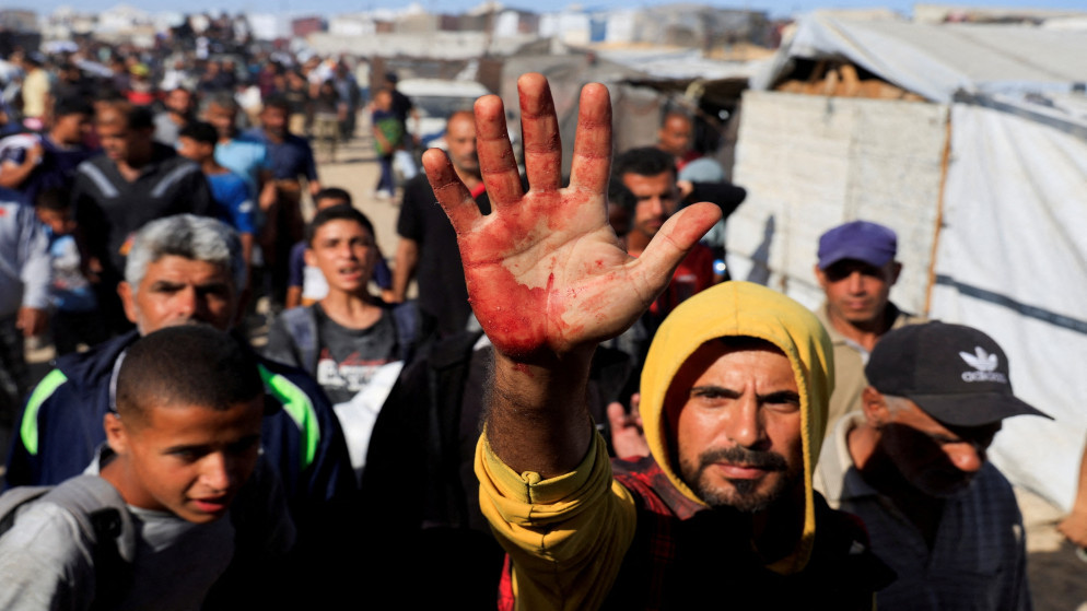 رجل فلسطيني يظهر بقع دماء على راحة يده بعد أن حمل مصابين بين أشخاص يسعون للحصول على إمدادات المساعدة من مؤسسة غزة الإنسانية المدعومة من الولايات المتحدة، في خان يونس، جنوبيّ قطاع غزة، 29 أيار 2025. رويترز