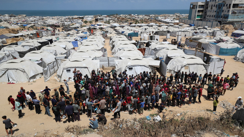 فلسطينيون ينتظرون الحصول على الطعام الذي أعدته جمعية خيرية بالقرب من الخيام التي لجأوا إليها بعد نزوحهم بسبب الهجوم العسكري الإسرائيلي في مدينة غزة، 28 أيار 2025 (رويترز)