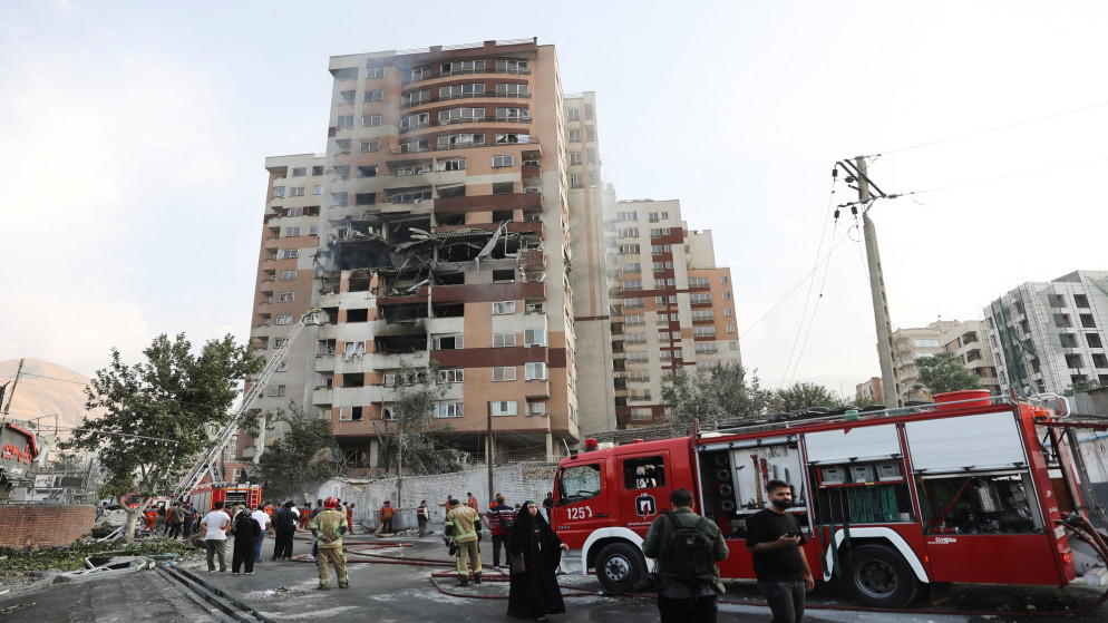 رجال إطفاء يعملون في موقع مبنى متضرر في أعقاب الغارات الإسرائيلية على طهران. 13/06/2025. (رويترز)