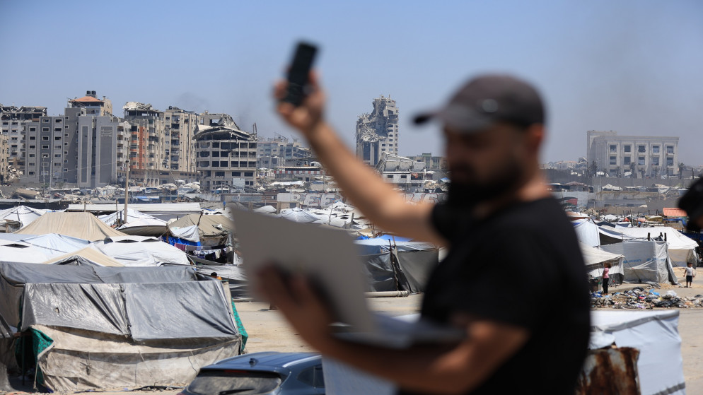 فلسطيني يحاول التقاط إشارة بث على هاتفه وسط قطاع غزة.