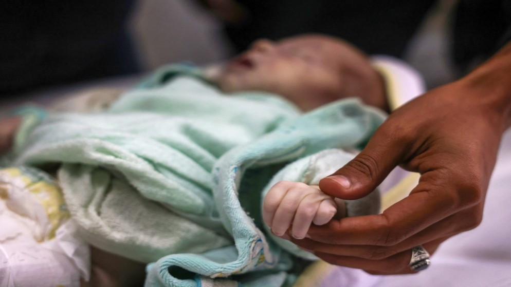 فلسطيني يمسك بيد ابنة أخته الشهيدة سيلا الفصيح، 3 أسابيع، في مشرحة مستشفى ناصر في خان يونس جنوبي غزة. 25/12/2024. (أ ف ب)