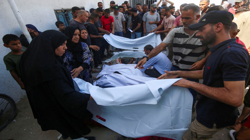فلسطينيون بجوار جثامين فلسطينيين استشهدوا بغارة إسرائيلية على كافتيريا الباقة. مستشفى الشفاء بمدينة غزة، 30 حزيران 2025. (رويترز)