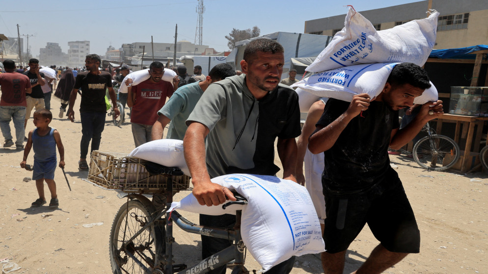 فلسطينيون يحملون أكياس طحين في خان يونس جنوب قطاع غزة، 26 حزيران 2025. (رويترز)