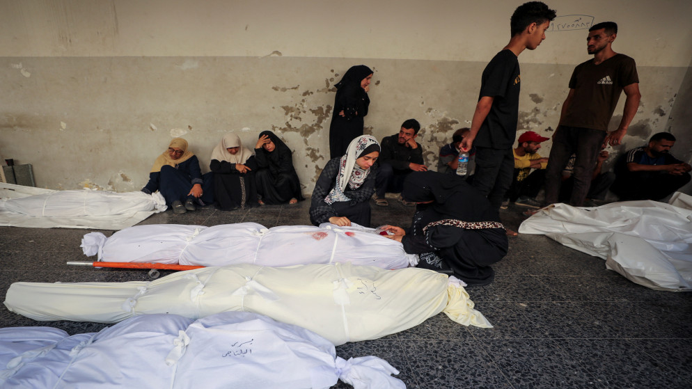 فلسطينيون بالقرب من جثامين في مستشفى الأهلي العربي في مدينة غزة، 5 تموز 2025. (رويترز)