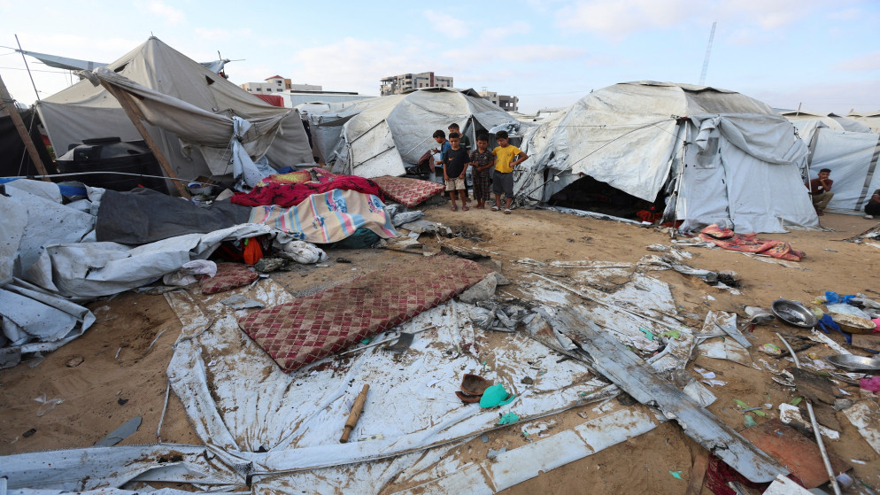 أطفال فلسطينيون يتفقدون الأضرار في موقع غارة جوية إسرائيلية ليلية أصابت خيمة تؤوي نازحين في خان يونس جنوبي قطاع غزة، 12 تموز 2025. (رويترز)