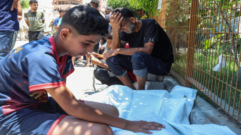 رجل فلسطيني مع ابنه، بجانب جثمان شهيد في مستشفى ناصر في خان يونس، جنوبي قطاع غزة، 12 تموز 2025. (رويترز)
