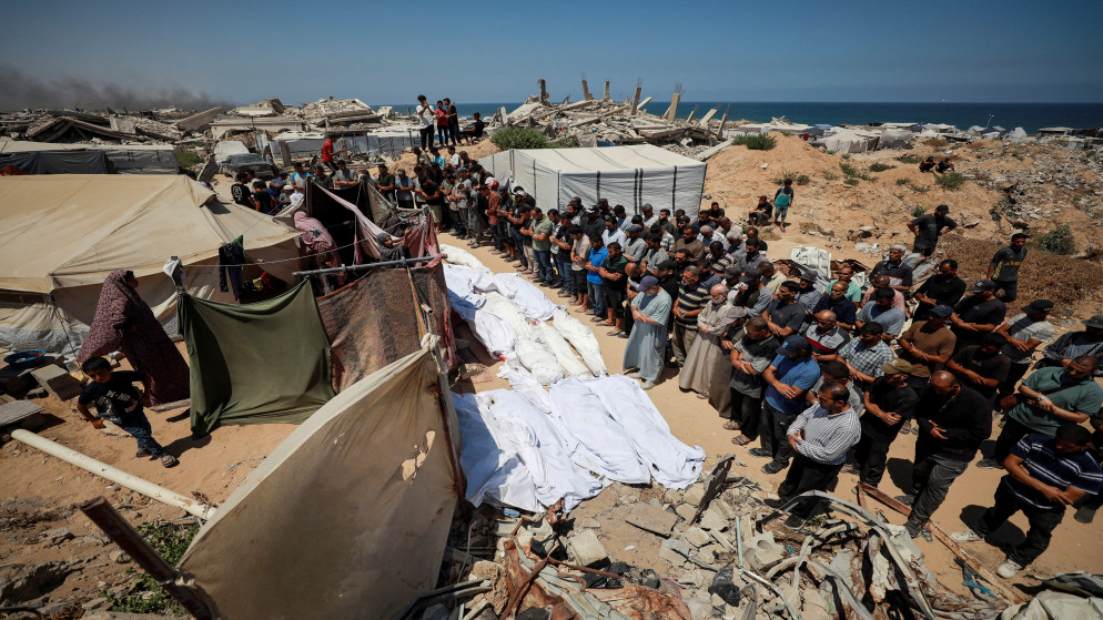فلسطينيون يصلون الجنازة على جثامين شهداء قبل دفنهم في قطعة أرض بسبب نقص المساحة في مقابر غزة المكتظة، في مدينة غزة 15 تموز 2025. (رويترز)