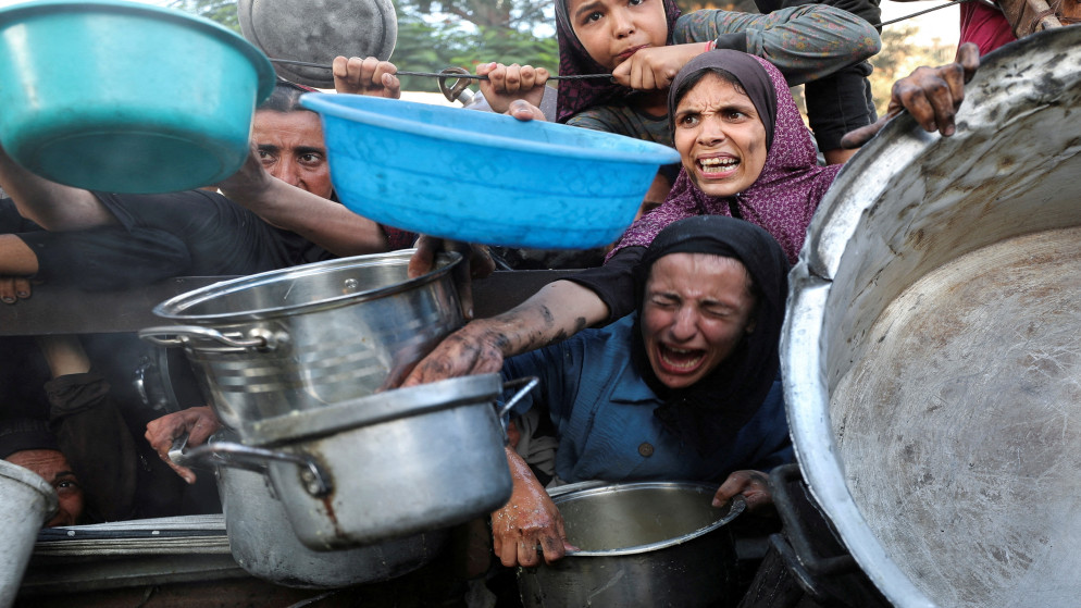 فلسطينيون ينتظرون دورهم لأخذ الطعام من مطبخ خيري، وسط أزمة جوع، في مدينة غزة، 14 تموز 2025. (رويترز)