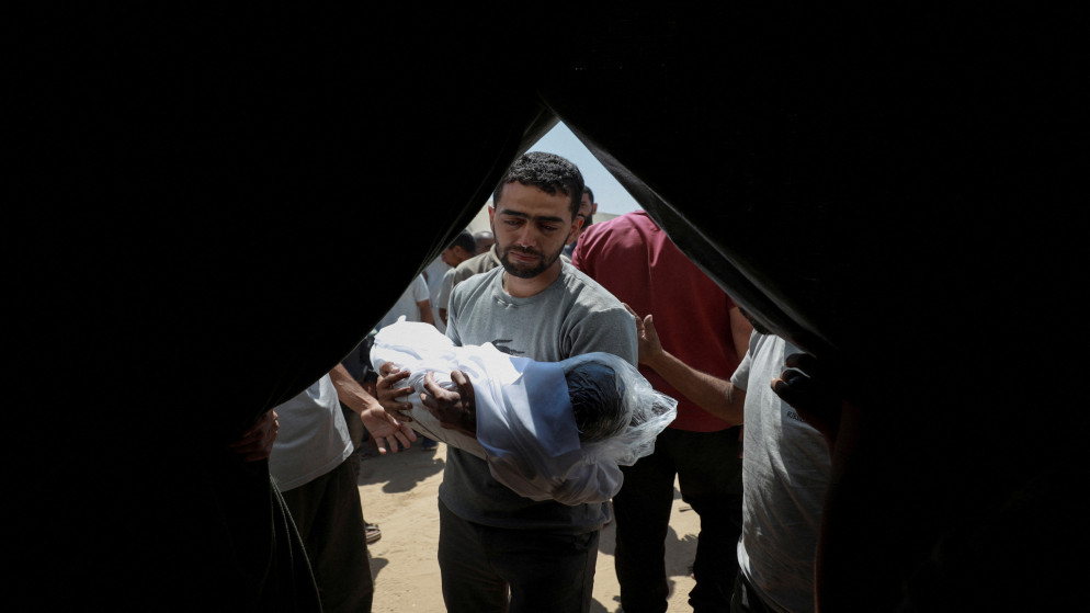 فلسطيني يحمل جثمان طفل شهيد في مدينة غزة 15 تموز 2025. (رويترز)
