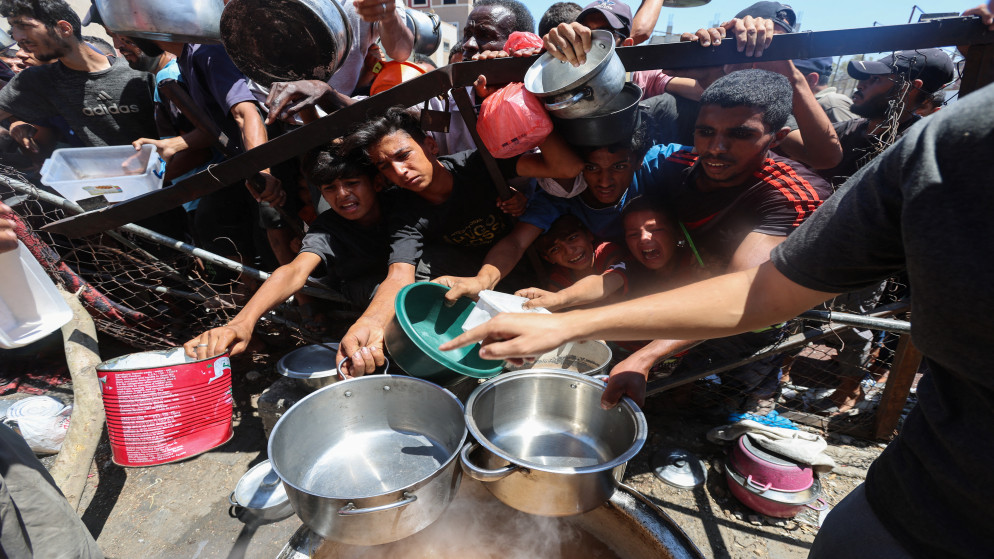 فلسطينيون يتجمعون لتلقي الطعام من مطبخ خيري، وسط أزمة جوع في النصيرات وسط قطاع غزة، 20 يوليو 2025. (رويترز)