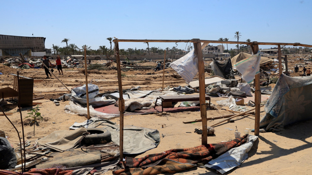 نازحون فلسطينيون يتفقدون الملاجئ المتضررة خلال عملية عسكرية إسرائيلية في دير البلح، وسط قطاع غزة، 22 يوليو/تموز 2025. (رويترز/حاتم خالد)