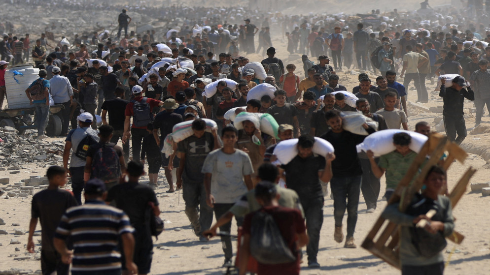 فلسطينيون يحملون إمدادات مساعدات شمال قطاع غزة، 27 تموز 2025. (رويترز)