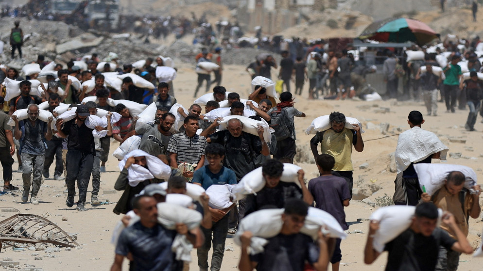 فلسطينيون يحملون مساعدات دخلت غزة في مدينة بيت لاهيا شمالي قطاع غزة. 27/07/2025. (رويترز)