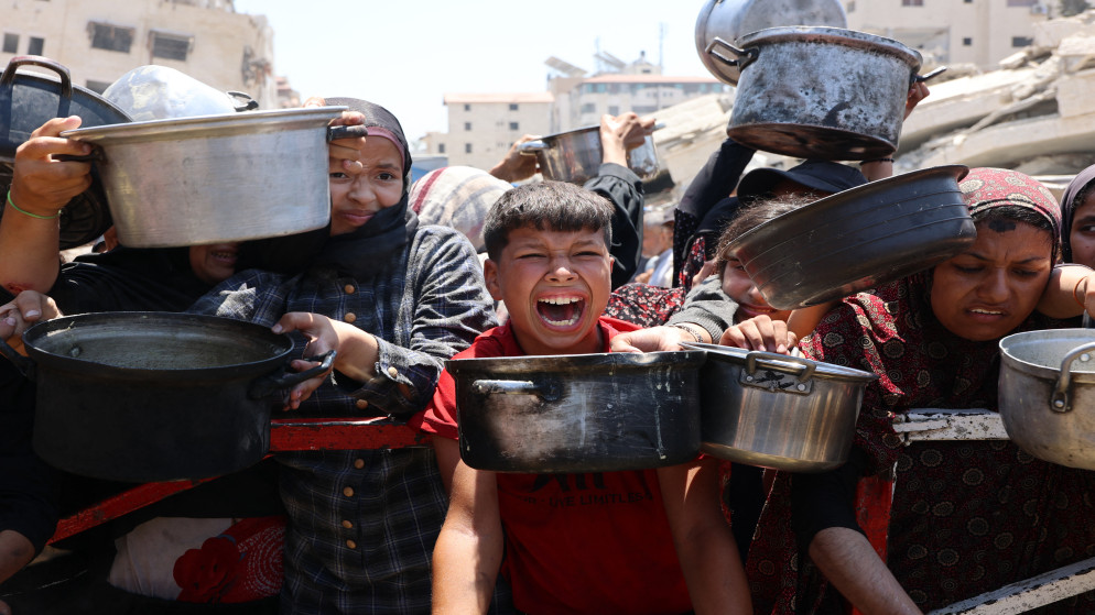 فلسطينيون يتجمعون عند نقطة توزيع حساء العدس في مدينة غزة شمال قطاع غزة،27 تموز 2025. (أ ف ب)