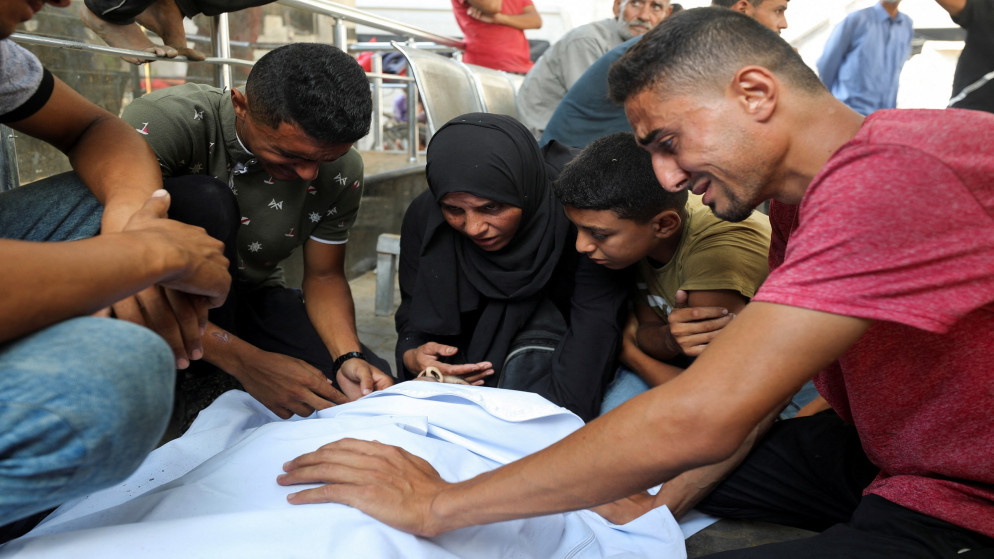 فلسطينيون بجوار جثمان قريب لهم استشهد بنيران الاحتلال الإسرائيلي في مدينة غزة. 29/07/2027. (رويترز)