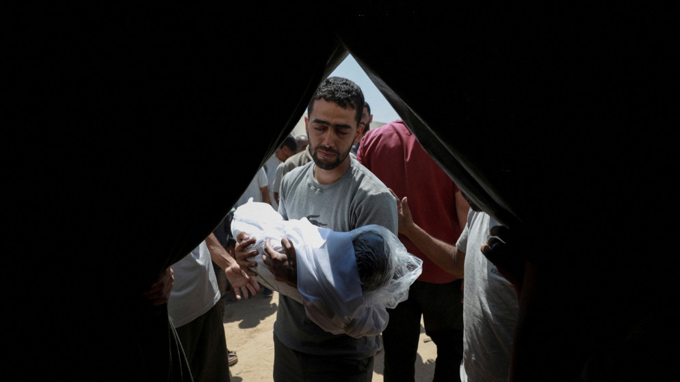 صورة أرشيفية لفلسطيني يحمل طفلا شهيدا في غارة إسرائيلية في قطاع غزة. (أ ف ب)