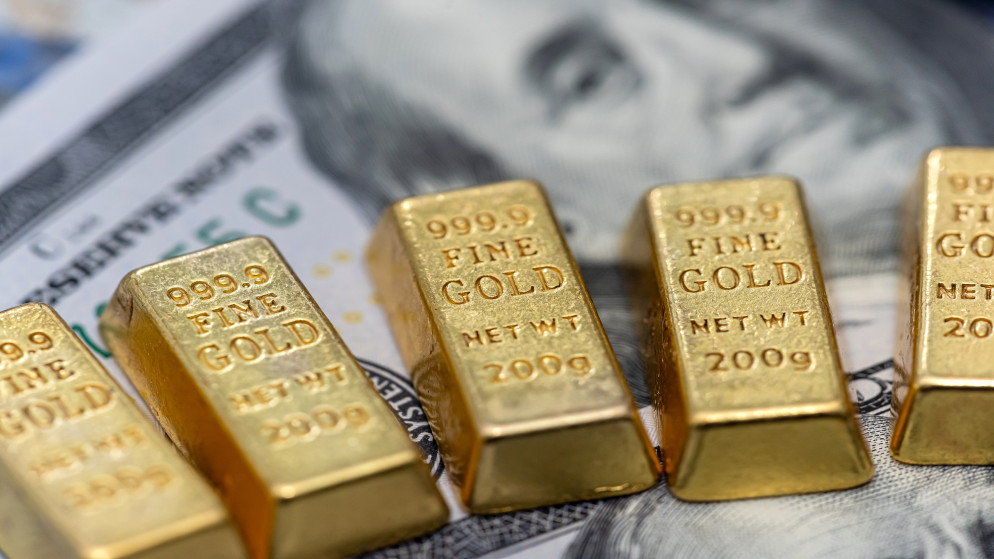 سبائك ذهبية على خلفية أوراق نقدية من فئة 100 دولار. (istockphoto)