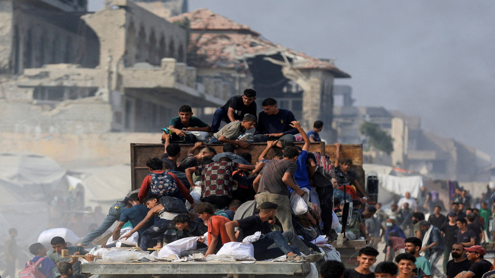 فلسطينيون يركبون شاحنة لجمع المساعدات التي دخلت غزة في بيت لاهيا، شمال قطاع غزة، 10 أغسطس/آب 2025. (رويترز)