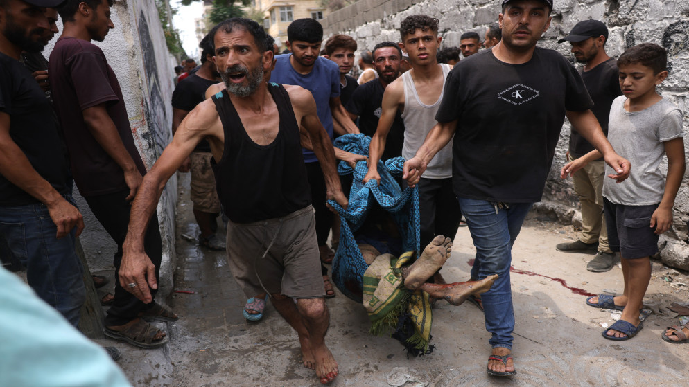 فلسطينيون يحملون جثمان شهيد في غارة إسرائيلية غربي مدينة غزة بتاريخ 12 آب 2025. (أ ف ب)