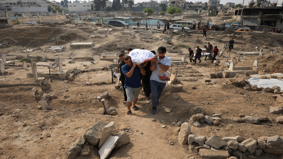 فلسطينيون يحملون جثمان شهيد داخل مقبرة لدفنه. 13 آب 2025. (رويترز)