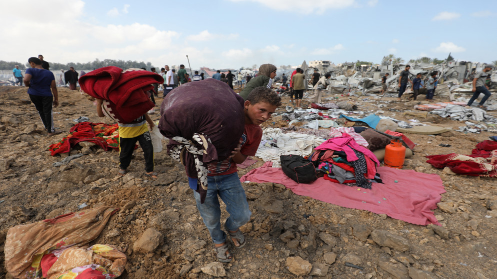 أطفال فلسطينيون يحملون أمتعتهم بعد غارة إسرائيلية على مخيم للنازحين في دير البلح وسط قطاع غزة، 21 آ ب 2025. (أ ف ب)