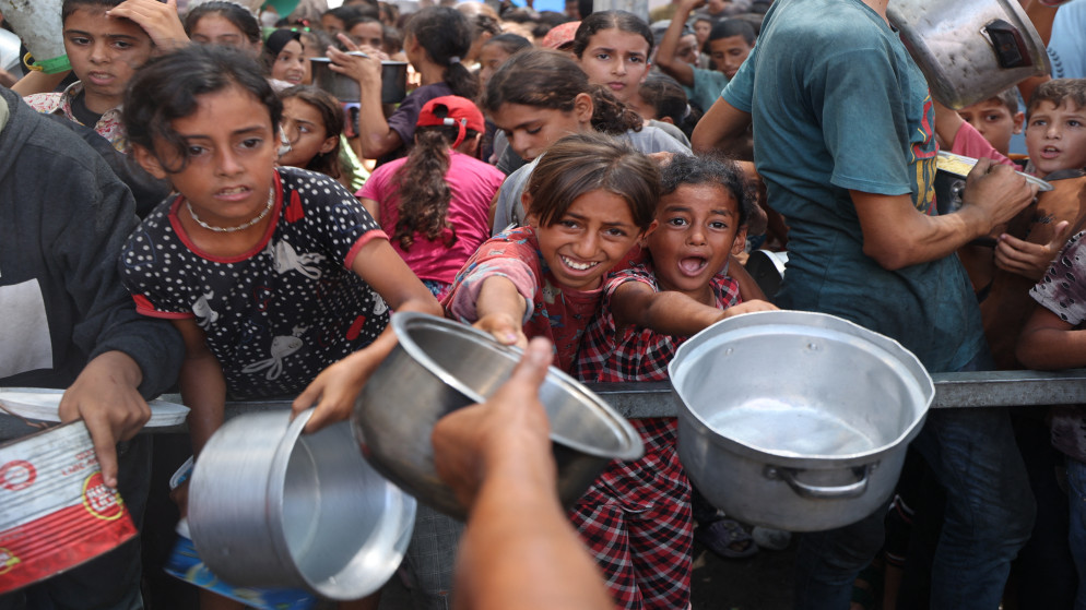 أطفال فلسطينيون يتلقون وجبات طعم من مركز توزيع الأغذية في مخيم النصيرات، 18 آب 2025. (أ ف ب)