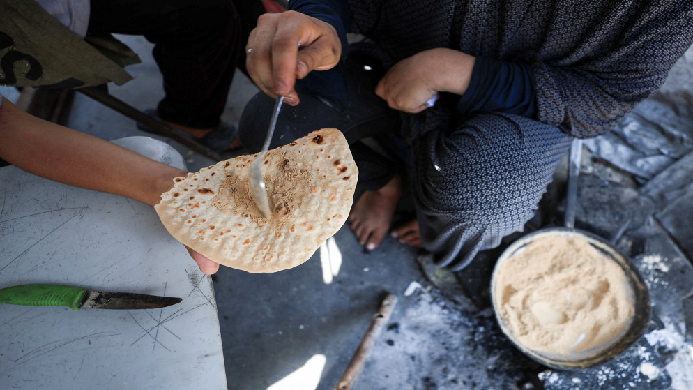 فلسطينية تقدم الدقة لطفلها داخل ملجأ خيمة وسط ندرة الغذاء وأزمة الجوع في مدينة غزة. 7 آب 2025. (رويترز)