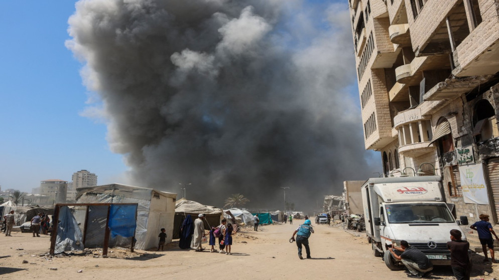 المواطنون يشاهدون تصاعد الدخان خلال غارة إسرائيلية على برج في مدينة غزة. 5 أيلول 2025. (أ ف ب)