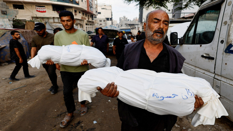فلسطيني يحمل جثمان طفل قضى نتيجة القصف الإسرائيلي المتواصل على قطاع غزة. (رويترز)