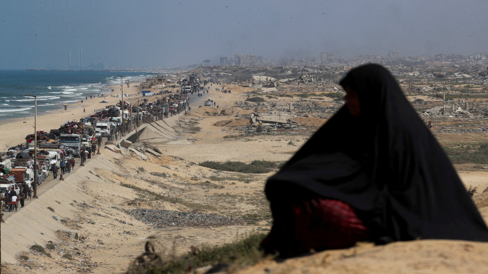 فلسطينية تراقب النازحين من شمال غزة بسبب العملية العسكرية الإسرائيلية، وهم يتحركون جنوبًا. 17 أيلول 2025. (رويترز)