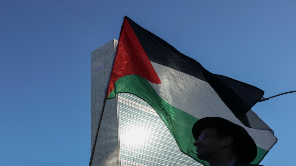 علم فلسطين يرفع من قبل أشخاص في وقفة أمام مقر الأمم المتحدة قبيل انعقاد الدورة الـ80 للجمعية العامة للأمم المتحدة. 18 أيلول 2025. (أ ف ب)