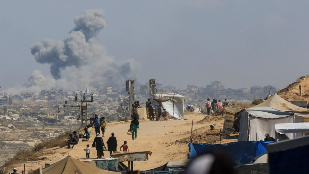 يتصاعد الدخان جراء غارة إسرائيلية بينما يتحرك فلسطينيون نازحون من شمال غزة بسبب العملية العسكرية الإسرائيلية نحو الجنوب. 24 أيلول 2025. (رويترز)