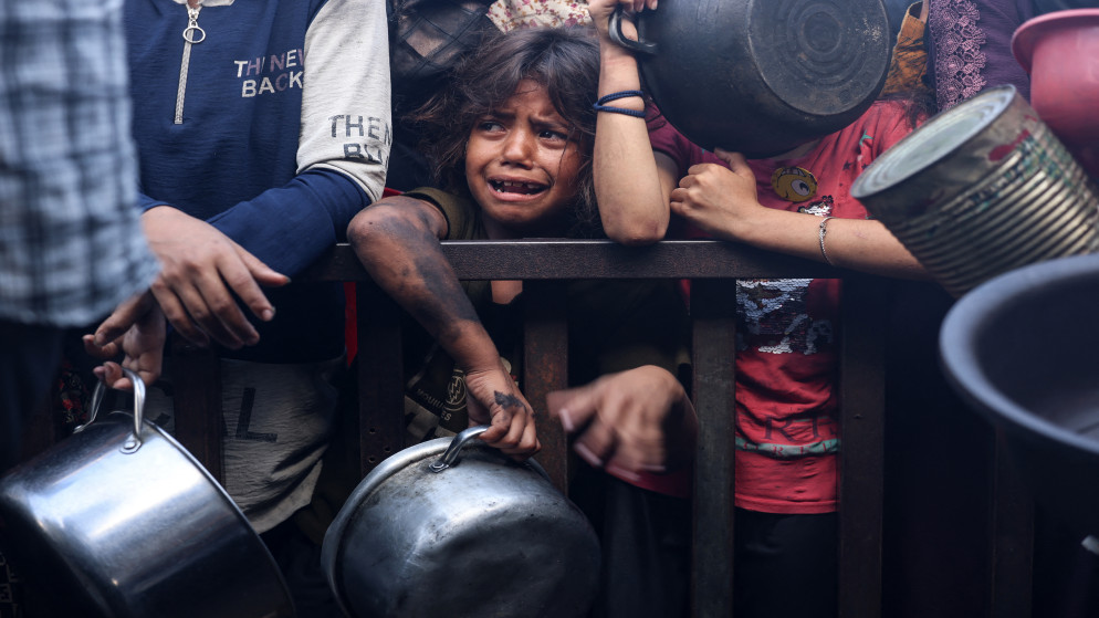 فتاة صغيرة مع نازحين فلسطينيين يحاولون الحصول على الطعام في خان يونس، جنوبي قطاع غزة، 19 أيلول 2025. (أ ف ب)