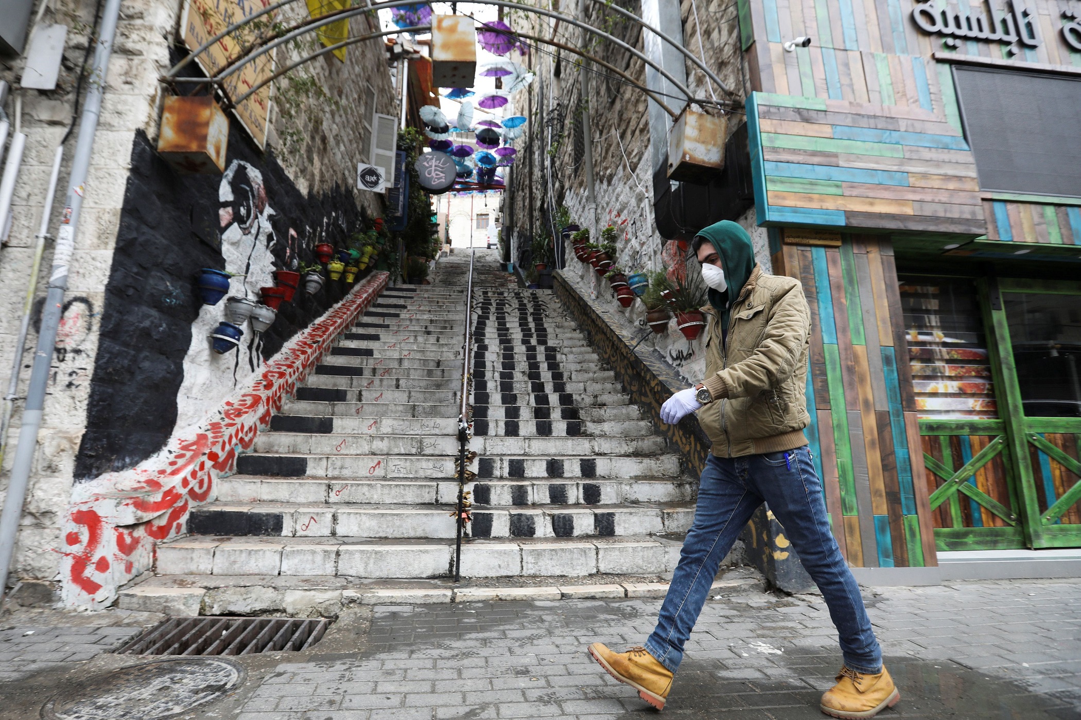 رجل يرتدي كمامة واقية بجوار محال مغلقة في وسط مدينة عمّان، 18 آذار/مارس 2020. (محمد حامد/ رويترز) 