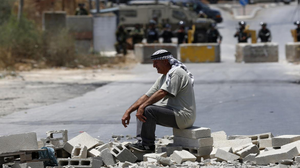 فلسطيني يجلس في مواجهة جنود الاحتلال الإسرائيلي أثناء مسيرة لرفض الاستيطان في بلدة بيتا بنابلس. 10/06/2021. (أيمن نوباني/ وفا)