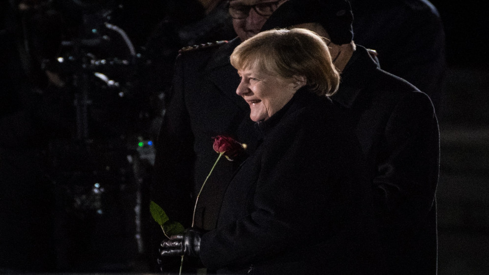 المستشارة الألمانية أنغيلا ميركل تحمل وردة حمراء وهي تغادر وزارة الدفاع خلال حفل وداعها في برلين. 02/12/2021. (ستيفاني لوس / أ ف ب)