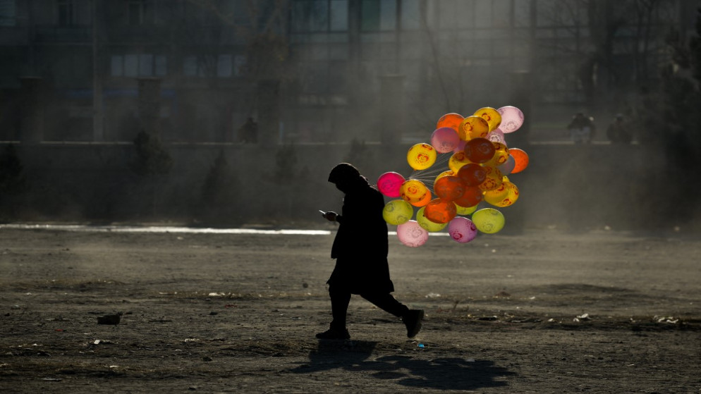بائع متجول أفغاني يبيع البالونات يسير على طول طريق في أرض في منطقة شامان هوزوري في كابل .10 كانون الأول/ ديسمبر 2021.(أ ف ب)