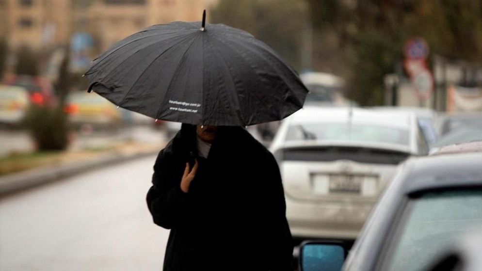 امرأة تحمل مظلة خلال يوم ماطر في الأردن. (صلاح ملكاوي/ المملكة)