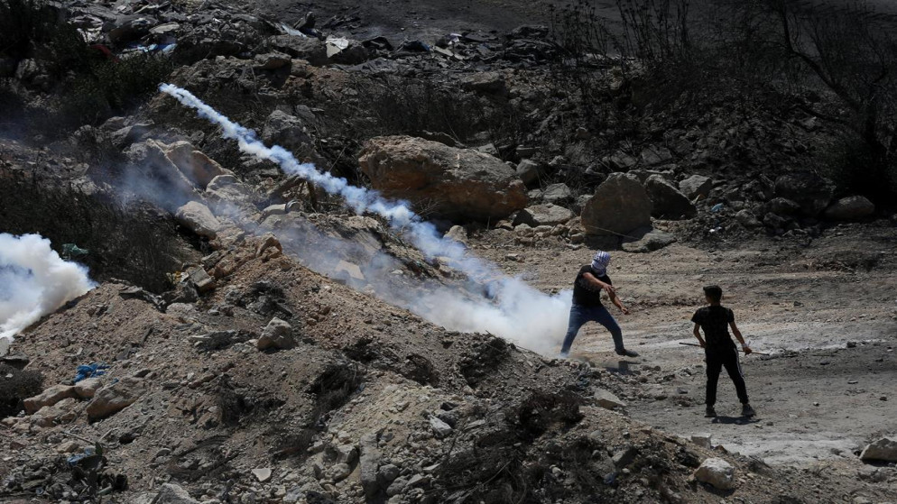 فلسطيني يرد قنبلة مسيلة للدموع ألقاها جيش الاحتلال الإسرائيلي جنوبي مدينة نابلس. 20/08/2021 (أيمن نوباني/ وفا)