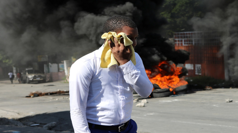 رجل يغطي وجهه أثناء سيره أمام حاجز مشتعل في الشارع خلال مظاهرات ضد عمليات الاختطاف الواسعة النطاق، في بورت أو برنس في هايتي، في 25 نوفمبر/تشرين الثاني 2021. (رويترز)