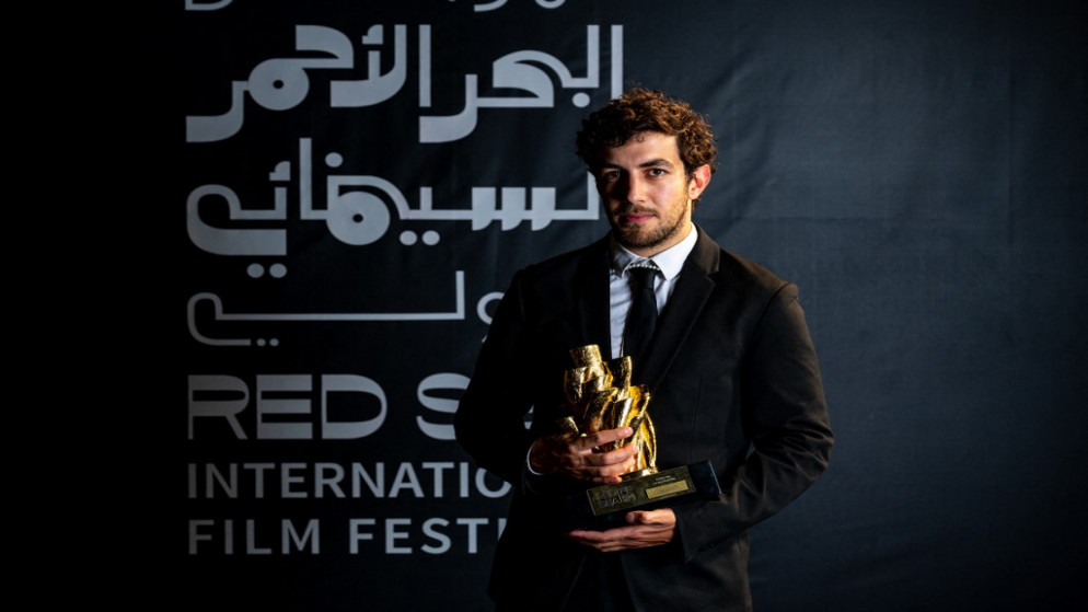 المخرج الأردني مراد أبو عيشة يحمل جائزة أفضل فيلم قصير عن فيلم "تالافيزيون" في مهرجان البحر الأحمر السينمائي الدولي. (أ ف ب)