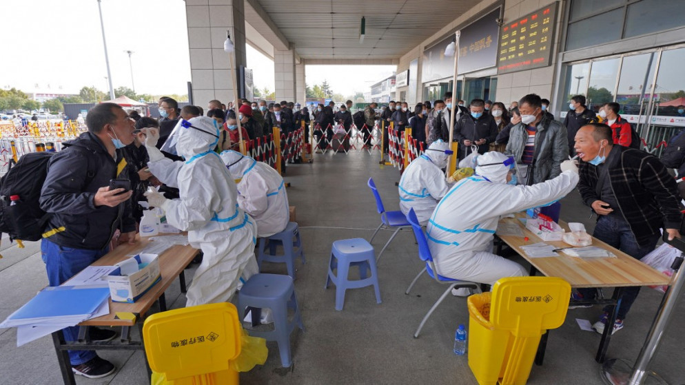 يُجري العاملون الصحيون اختبارات فيروس كورونا على المسافرين عند مخرج محطة سكة حديد Yantai في مقاطعة Shandong شرقي الصين .2 نوفمبر 2021.(أ ف ب)