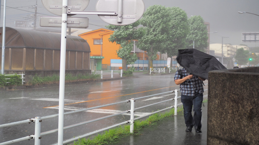 صورة توضيحية لرجل يحمل مظلة على الرصيف خلال عاصفة. (shutterstock)