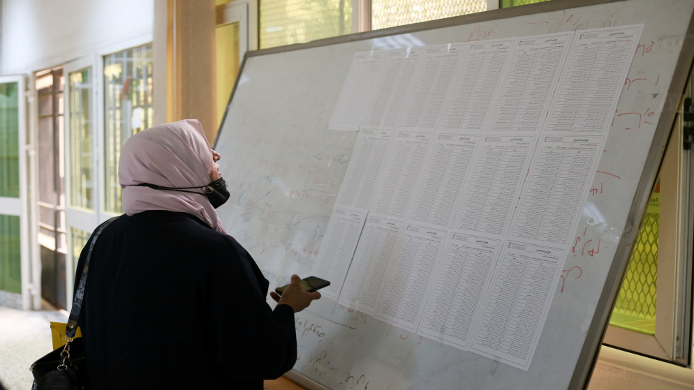 امرأة تتحقق من الأسماء لاستلام بطاقتها الانتخابية داخل مركز اقتراع في طرابلس الغرب. (رويترز)