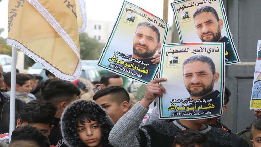 معتصمون يحملون صور الأسير الفلسطيني المضرب عن الطعام هشام أبو هواش خلال وقفة في الخليل، 07/12/2021. (مشهور وحواح/ وفا)