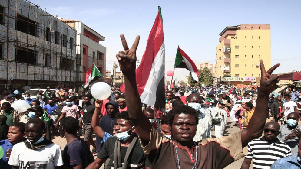 سودانيون يرفعون الأعلام الوطنية أثناء احتجاجات في الجزء الشمالي من العاصمة الخرطوم. 19/12/2021. (أ ف ب)