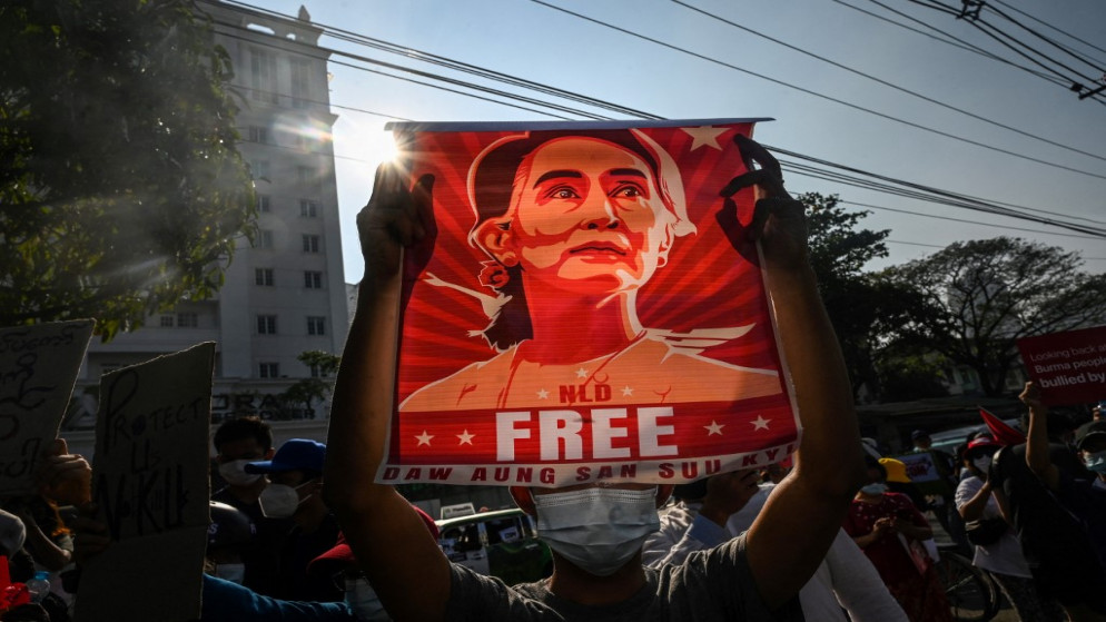 شخص يحمل ملصقًا يظهر أونغ سان سو تشي خلال مظاهرة ضد الانقلاب العسكري أمام البنك المركزي لميانمار في يانغون. 15/02/2021. (أ ف ب)