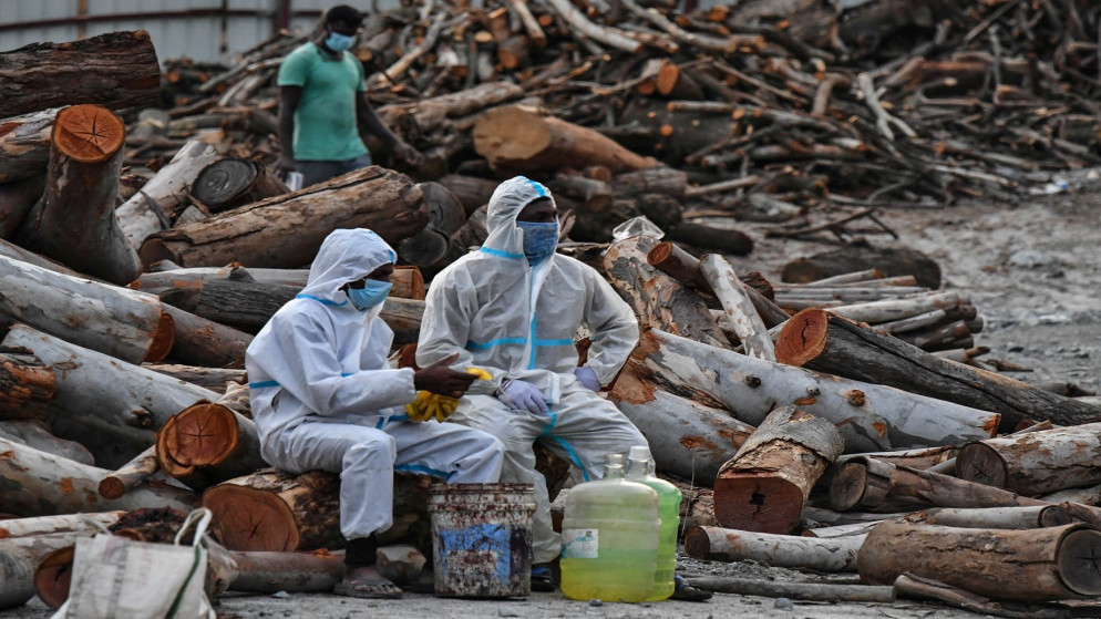 متطوعون يأخذون استراحة أثناء حرق جثث الموتى بسبب مرض فيروس كورونا في ضواحي بنغالورو، الهند، 13 أيار/ مايو 2021 (رويترز)